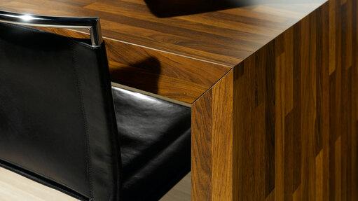 Detailaufnahme eines Esstisches aus Massivholz Detailaufnahme eines Esstisches aus dunklem Massivholz in Kombination mit Ledersessel